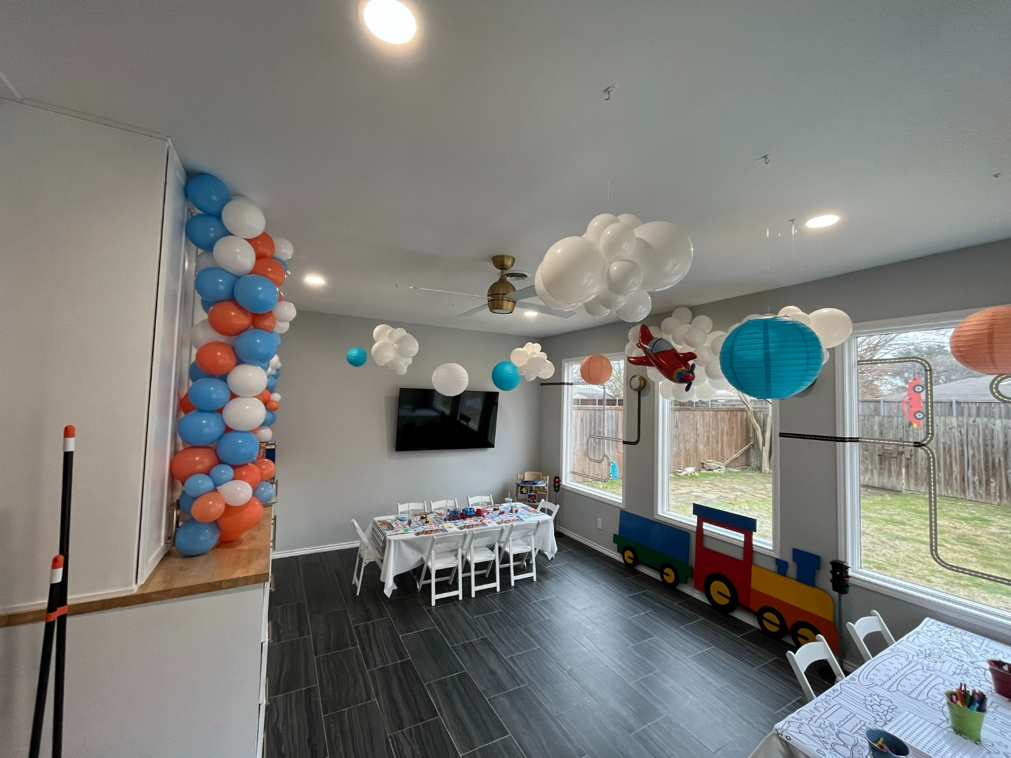 Transportation themed first birthday party room with balloon column and cloud installation