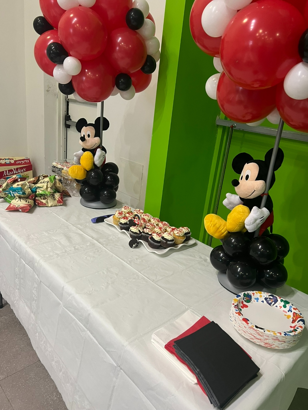 Mickey Mouse dessert table with Mickey plush balloon topiaries and decorated cupcakes