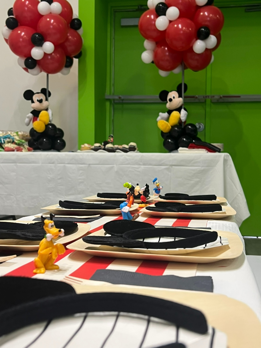 Mickey Mouse party table closeup with Pluto and Goofy figurines on striped runner