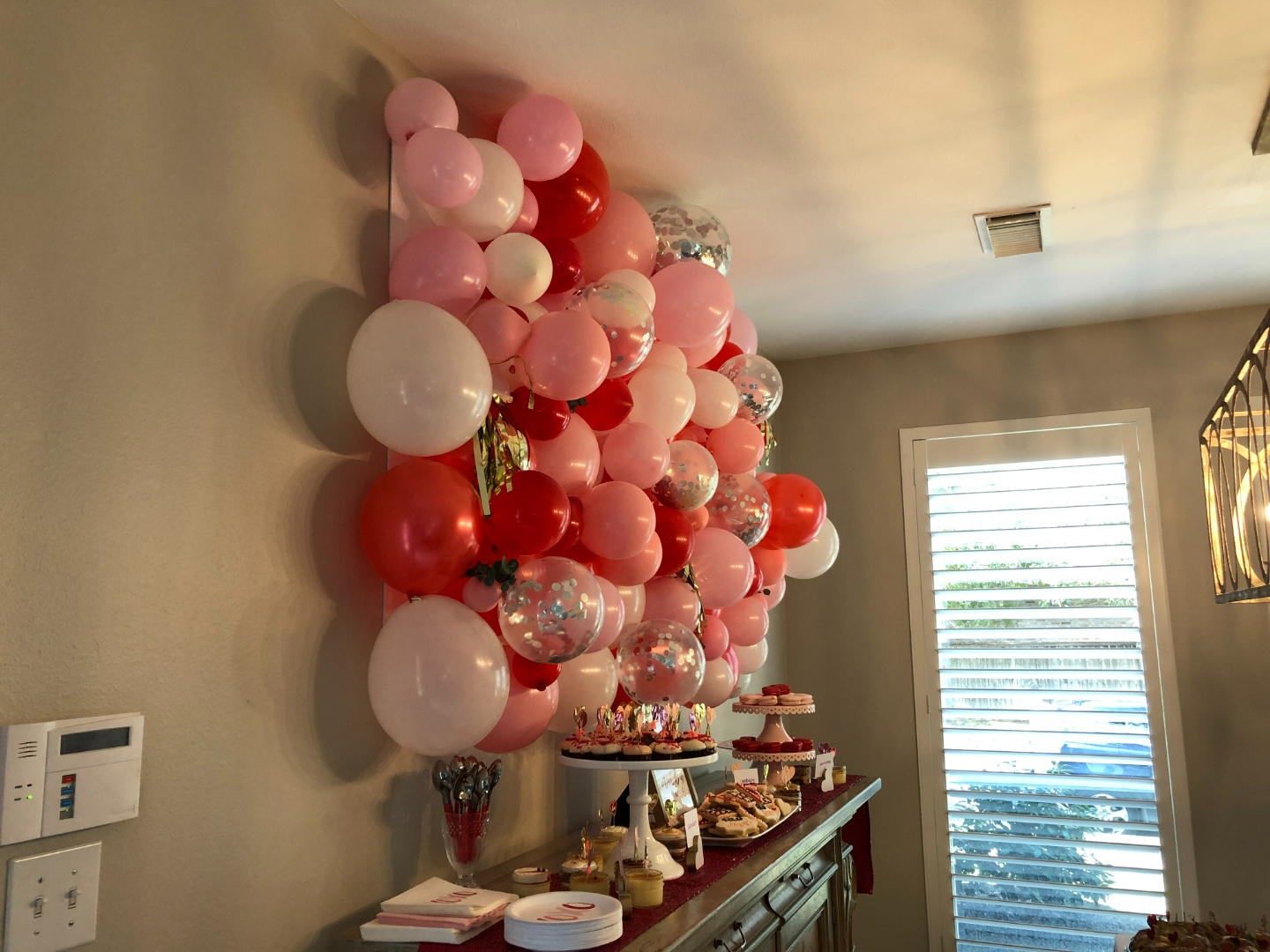Side view of the balloon wall installation spanning the full wall above the antique sideboard dessert display